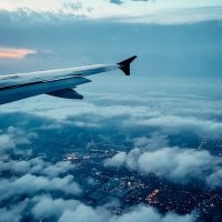 A stunning aerial view from an airplane window, showcasing clouds and city lights below.
